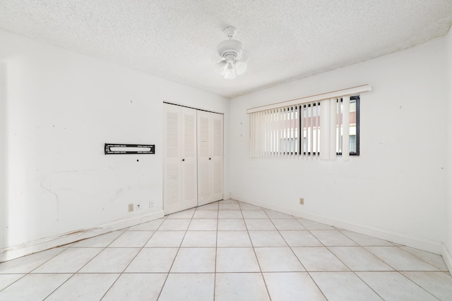 tiled spare room with ceiling fan and a textured ceiling