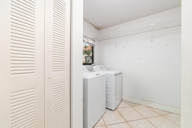 clothes washing area featuring a textured ceiling, light tile patterned floors, and washing machine and clothes dryer