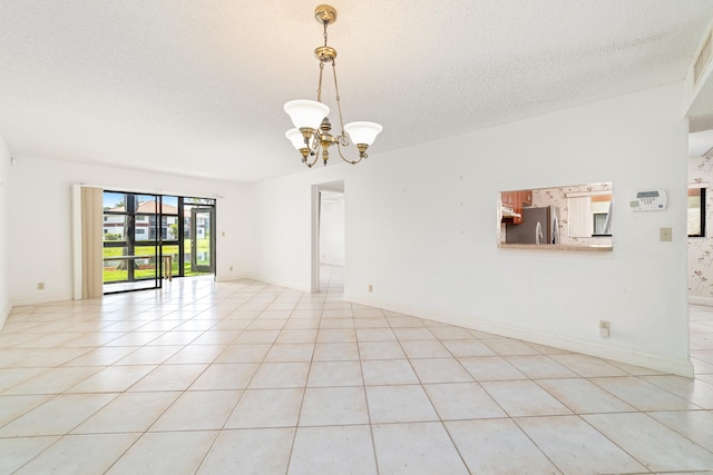 unfurnished room featuring a textured ceiling, a chandelier, and light tile patterned flooring