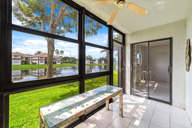 sunroom featuring ceiling fan and a water view