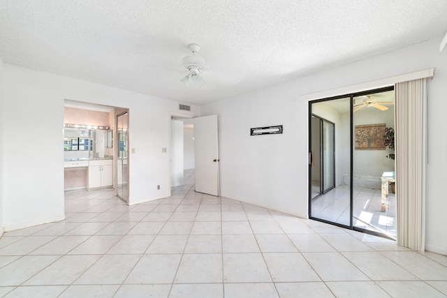 tiled empty room with ceiling fan and a textured ceiling