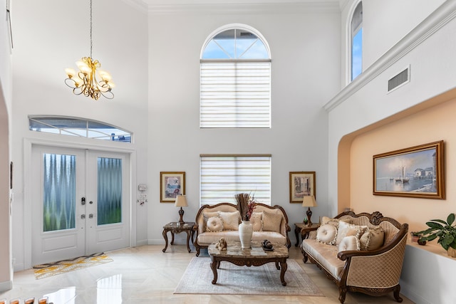 entrance foyer featuring ornamental molding, french doors, a high ceiling, and a chandelier