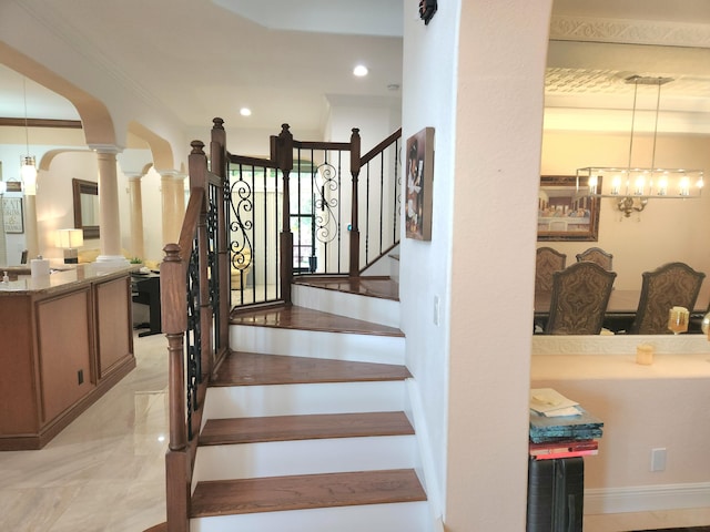 stairway with ornamental molding and an inviting chandelier