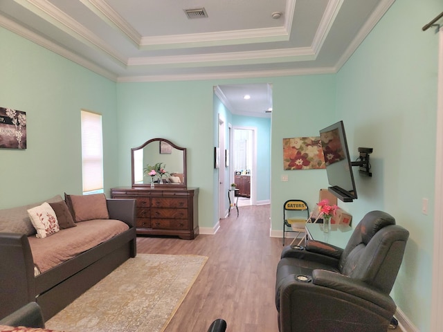 living room featuring a raised ceiling, light hardwood / wood-style flooring, and crown molding