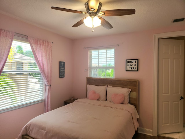 bedroom featuring ceiling fan, a textured ceiling, and multiple windows