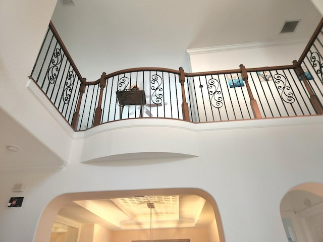 stairs featuring a raised ceiling, a towering ceiling, and crown molding