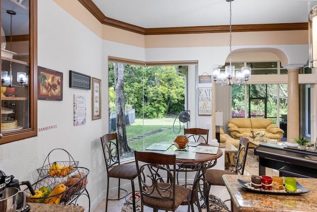 dining area featuring decorative columns, ornamental molding, and an inviting chandelier