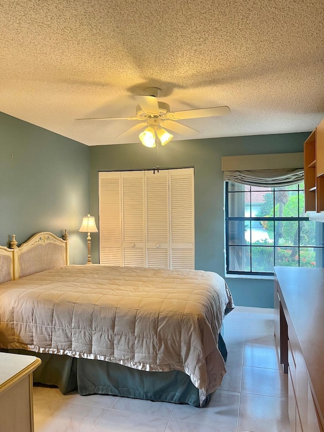 bedroom featuring a textured ceiling, light tile patterned floors, and ceiling fan