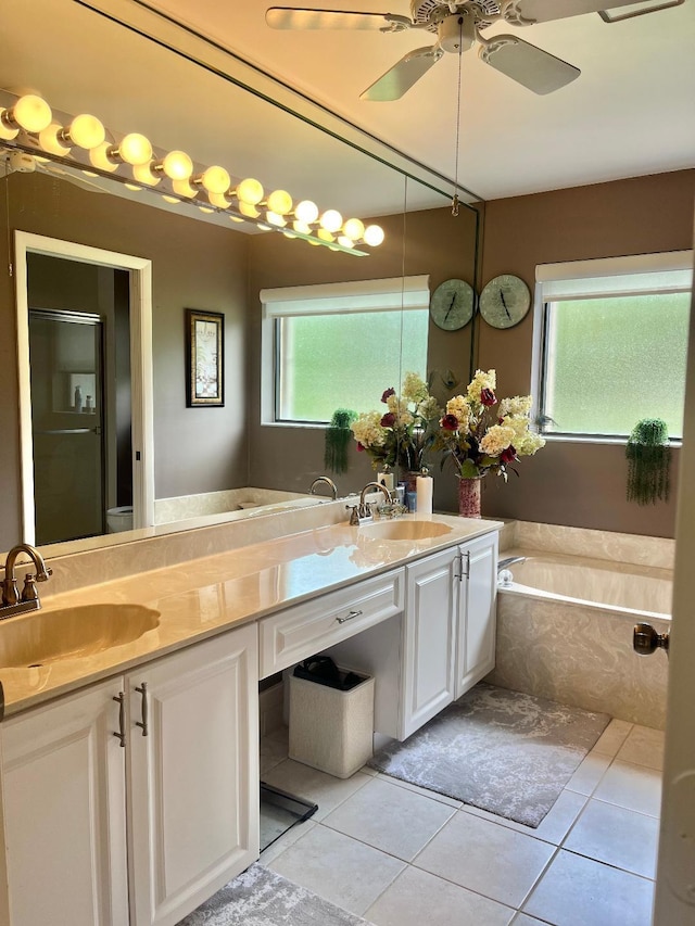 bathroom featuring tile patterned flooring, a wealth of natural light, vanity, and tiled tub