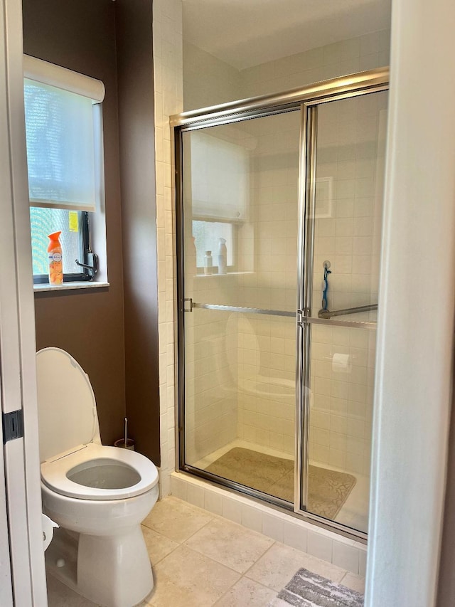 bathroom featuring toilet, tile patterned flooring, and a shower with shower door