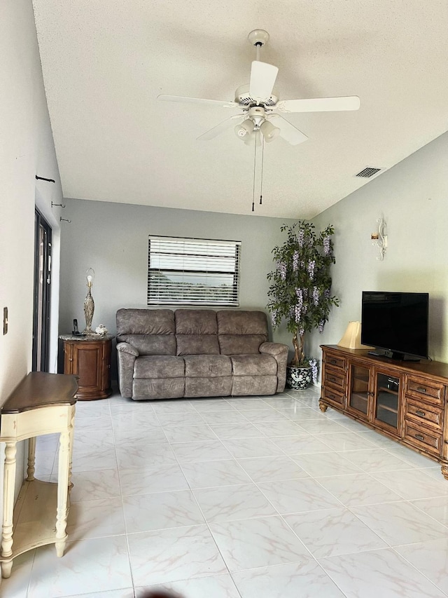 living room featuring vaulted ceiling, ceiling fan, and a textured ceiling