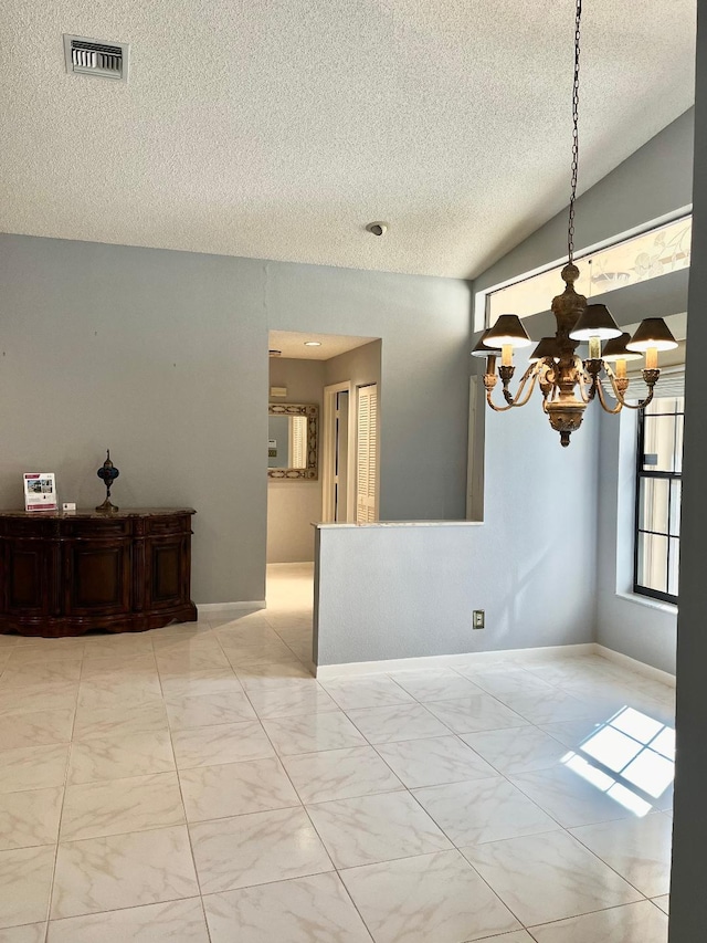 empty room with a textured ceiling, an inviting chandelier, and lofted ceiling