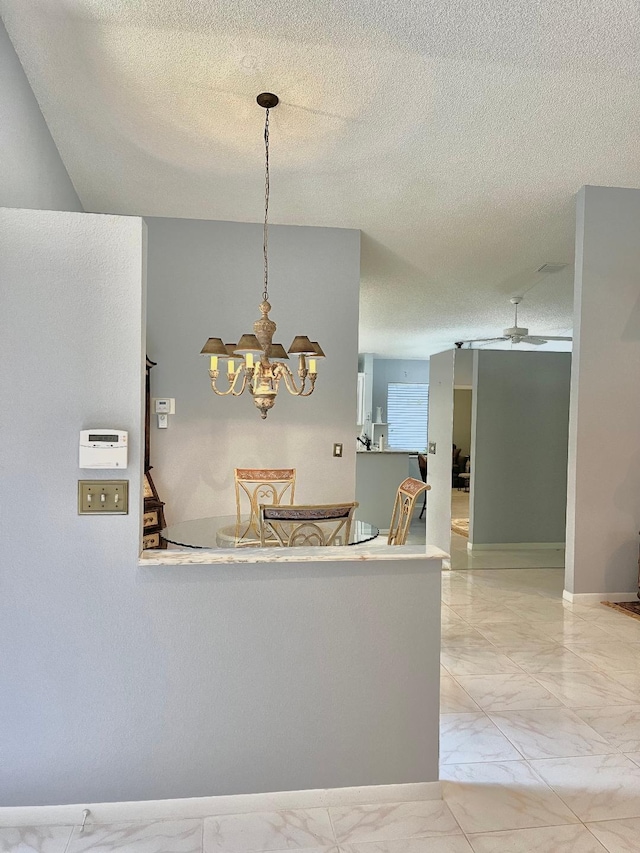 dining area featuring ceiling fan with notable chandelier and a textured ceiling