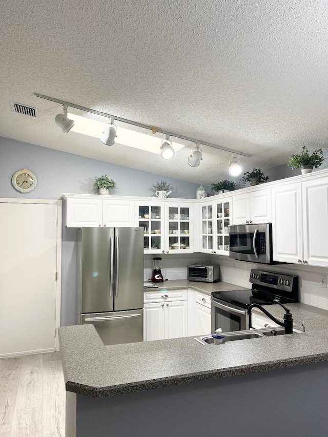 kitchen with stainless steel appliances, white cabinetry, light wood-type flooring, and rail lighting