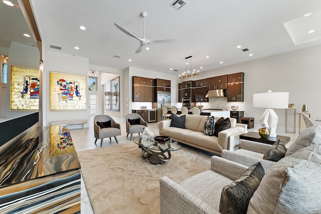 tiled living room with ceiling fan with notable chandelier