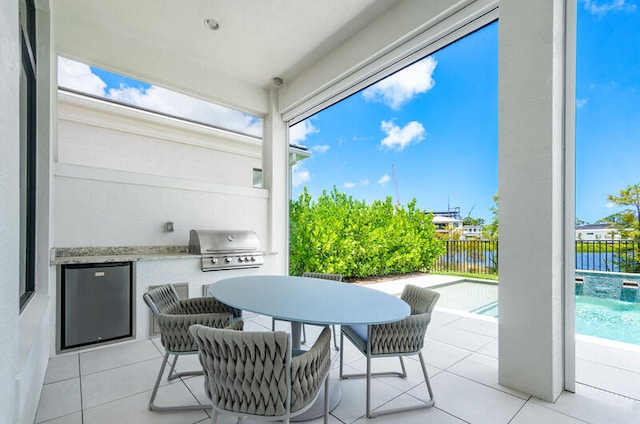 view of patio featuring area for grilling, a fenced in pool, a water view, and exterior kitchen