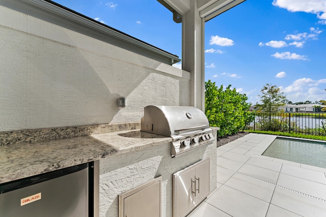 view of patio / terrace featuring area for grilling, a water view, and exterior kitchen