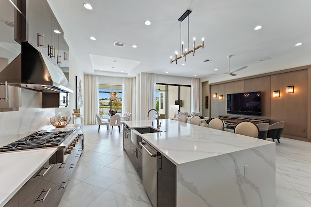 kitchen featuring hanging light fixtures, sink, a large island with sink, stainless steel appliances, and ceiling fan with notable chandelier