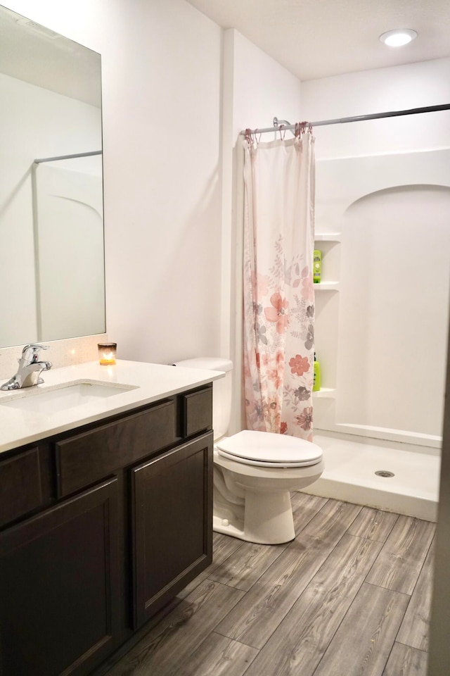 bathroom featuring hardwood / wood-style floors, toilet, vanity, and curtained shower