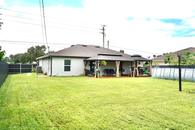 rear view of property featuring a gazebo, a yard, and central air condition unit