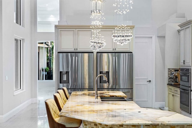 6595 NW 32nd Ter, Boca Raton, FL 33496 - kitchen with stainless steel fridge, a chandelier, baseboards, a high ceiling, and light stone countertops