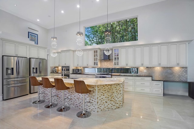6595 NW 32nd Ter, Boca Raton, FL 33496 - kitchen with stainless steel appliances, a towering ceiling, decorative backsplash, a kitchen bar, and light stone countertops