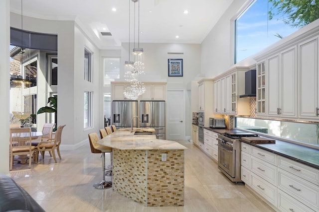 6595 NW 32nd Ter, Boca Raton, FL 33496 - kitchen featuring stainless steel appliances, a high ceiling, a sink, wall chimney range hood, and a breakfast bar area