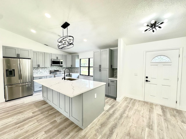 kitchen featuring stainless steel appliances, a kitchen island with sink, gray cabinetry, and sink