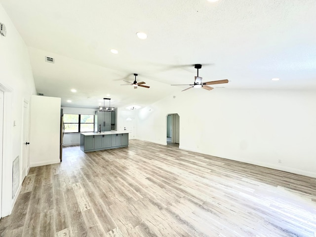 unfurnished living room with ceiling fan, lofted ceiling, and light wood-type flooring