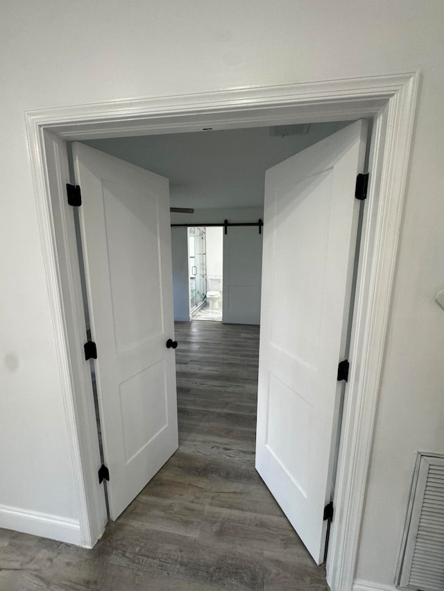 hallway featuring a barn door and dark wood-type flooring