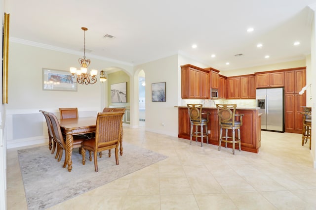 tiled dining area featuring crown molding and a chandelier