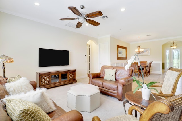 carpeted living room with ceiling fan with notable chandelier and crown molding