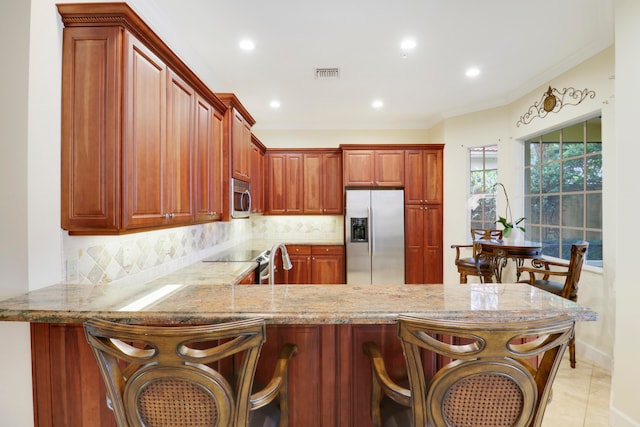 kitchen featuring a kitchen bar, appliances with stainless steel finishes, kitchen peninsula, and decorative backsplash