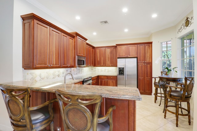 kitchen with ornamental molding, a breakfast bar, kitchen peninsula, and appliances with stainless steel finishes