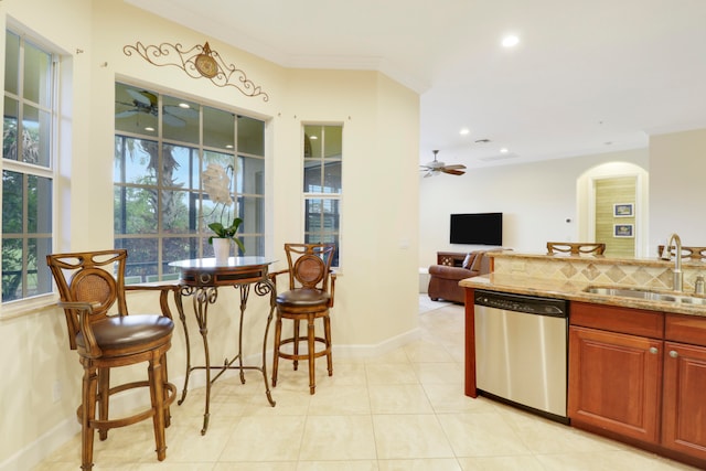 kitchen featuring light stone countertops, a wealth of natural light, sink, and stainless steel dishwasher