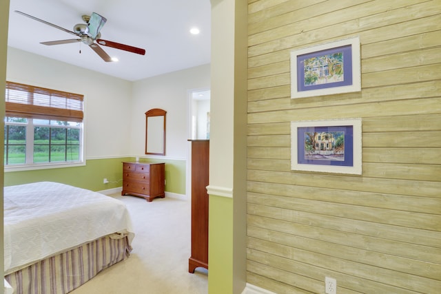 carpeted bedroom featuring wood walls and ceiling fan