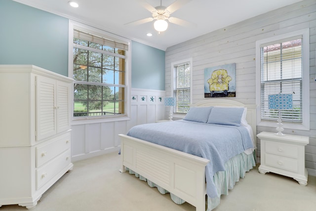 carpeted bedroom featuring ceiling fan, wooden walls, and multiple windows