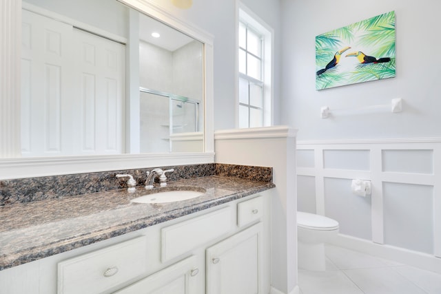 bathroom featuring vanity, toilet, tile patterned floors, and a shower with shower door