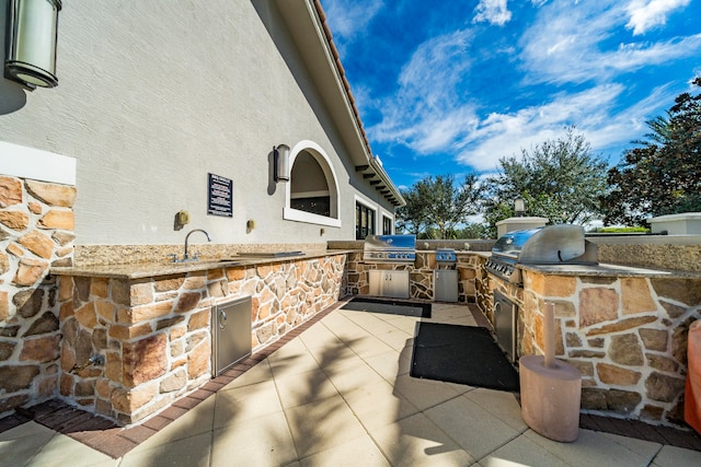 view of patio / terrace with area for grilling, a grill, and sink