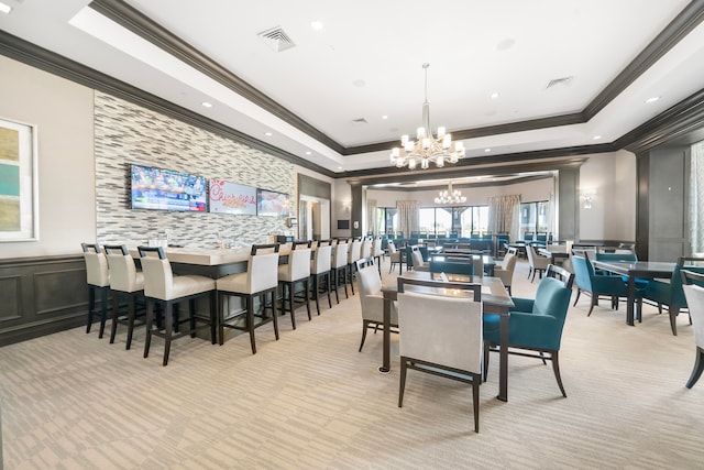 dining space with crown molding, light carpet, a chandelier, and a raised ceiling