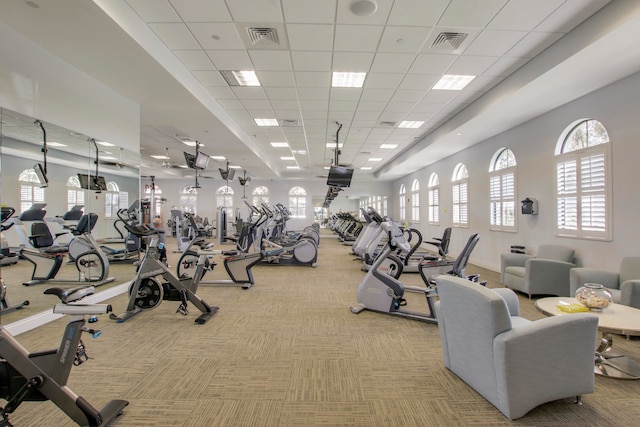 workout area with a paneled ceiling and light carpet