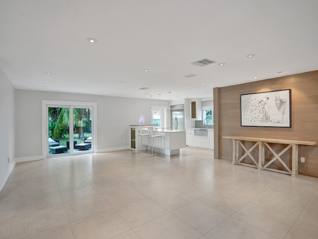 unfurnished living room featuring light tile patterned flooring and sink