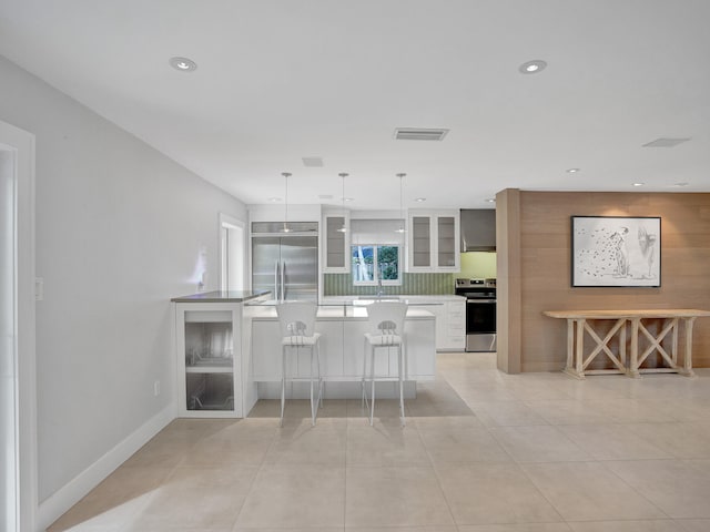 kitchen with appliances with stainless steel finishes, hanging light fixtures, a kitchen breakfast bar, white cabinets, and sink