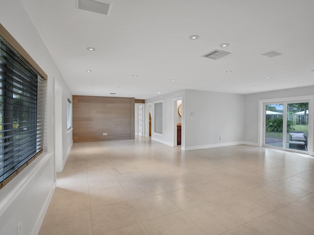 unfurnished room featuring wooden walls and light tile patterned floors