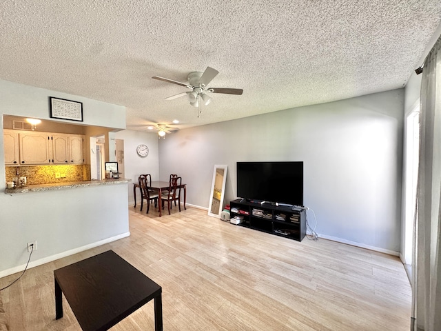 living room featuring a textured ceiling, light hardwood / wood-style floors, and ceiling fan