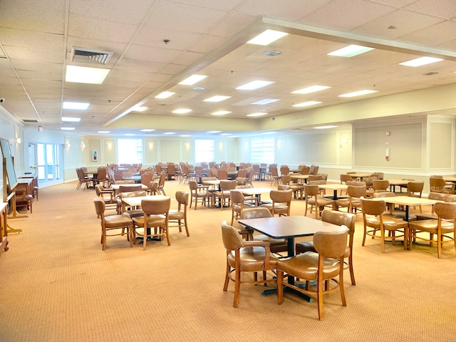 dining space with a paneled ceiling and light colored carpet