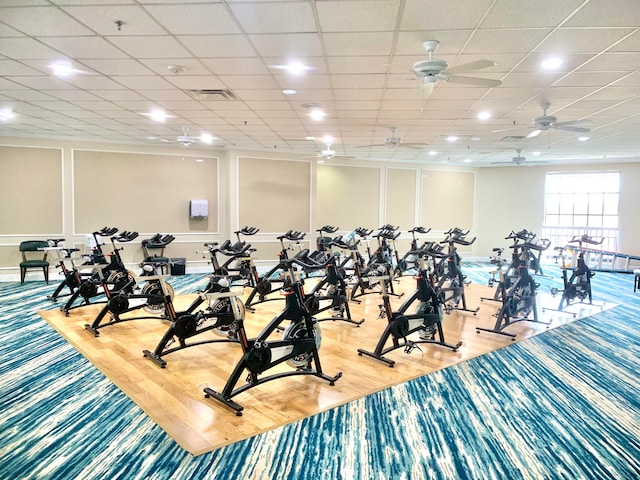 workout area featuring a paneled ceiling, ceiling fan, and wood-type flooring