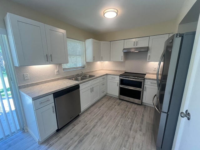 kitchen featuring appliances with stainless steel finishes, light hardwood / wood-style floors, sink, and white cabinets