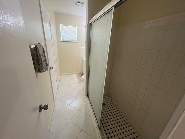 bathroom featuring tile patterned flooring, toilet, and an enclosed shower