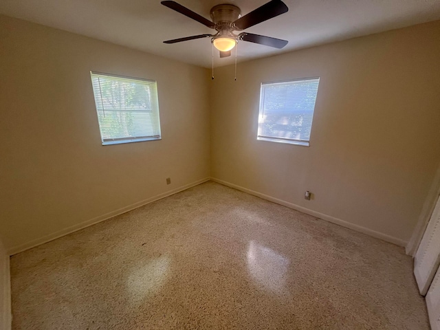 empty room with ceiling fan and plenty of natural light